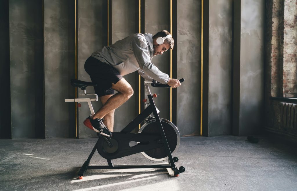 Young man in headphones cycling in gym